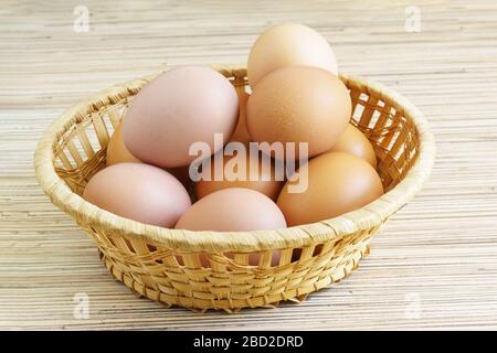 Echte Bauernhof Hühnereier liegen in einem Weidenkorb auf dem Tisch. Essen Stockfoto