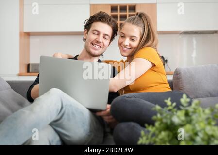 Verbinden Sie das Gerät mit dem schnellen Internet zu Hause mit einem Laptop. Frau und Mann auf dem Sofa im Wohnzimmer Stockfoto