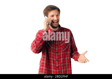 Junger kaukasischer Mann mit Handy isoliert auf weißem Studiohintergrund. Konzept moderner Technologien, Gadgets, Technologien, Emotionen, Werbung. Copyspace. Reden, lächeln, glücklich. Stockfoto