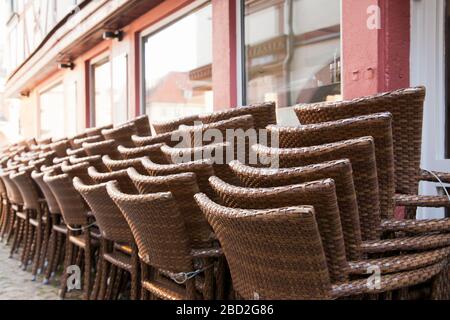 Gestapelte Stühle vor einem Café oder Restaurant in einer historischen Innenstadt - im Vordergrund stehen die Stühle Stockfoto