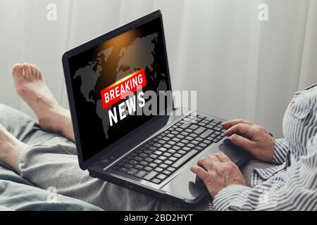 Coronavirus, Kovid-19 Breaking News. Eine Frau mit einem Laptop beobachtet die Nachrichten, die auf einem Sofa im Haus sitzen. Bleiben Sie in Quarantäne Stockfoto