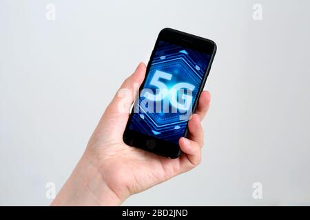 Ein generisches Bild eines 5g-Bildes/Logos, das auf einem Smartphone angezeigt wird, das in einer Hand gehalten wird. Stockfoto