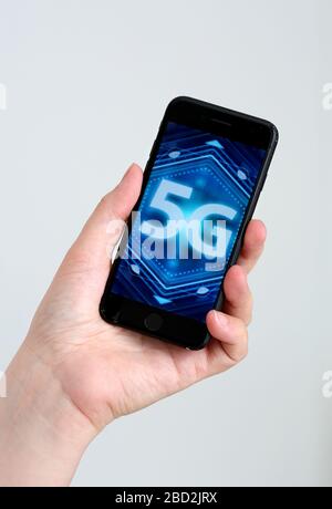 Ein generisches Bild eines 5g-Bildes/Logos, das auf einem Smartphone angezeigt wird, das in einer Hand gehalten wird. Stockfoto