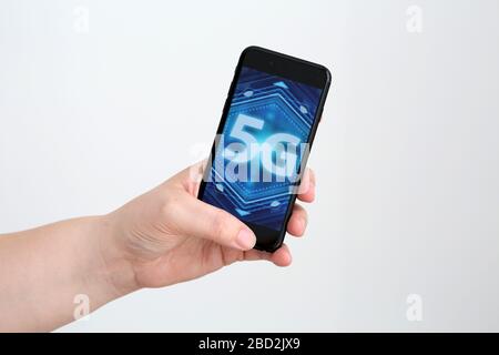 Ein generisches Bild eines 5g-Bildes/Logos, das auf einem Smartphone angezeigt wird, das in einer Hand gehalten wird. Stockfoto