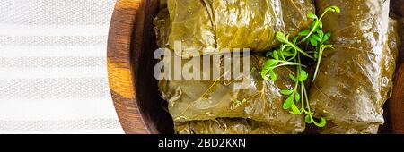 dolma (sarma) gefüllte Traubenblätter auf Holzplatte. Libanon türkische griechische mittelöstliche Küche. Dolmadakia oder Dolma. Yaprak sarma an Serviette Stockfoto