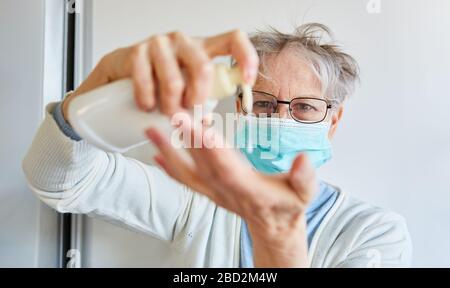 Ältere Frauen mit Gesichtsmaske bringen flüssige Seife an den Händen, bevor sie die Hände waschen, wegen des Covid-19- und Corona-Virus Stockfoto