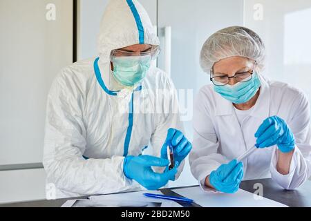Forscher arbeiten an Covid-19-Medikamenten und Impfungen in Schutzkleidung im Labor während einer Coronavirus-Epidemie Stockfoto