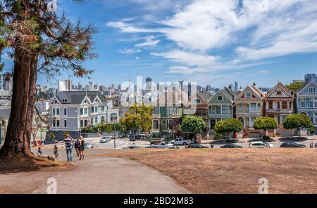 San Francisco, CA/USA - 17. Juli 2015: Die bemalten Damen in der Steiner Street mit Blick auf den Alamo Square und die moderne Skyline der Stadt. Stockfoto