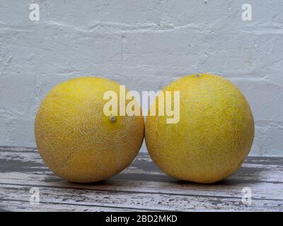 Nahaufnahme von zwei Galia Melonen auf dem Tisch vor weißem Hintergrund Stockfoto