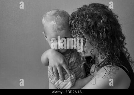 Verängstigte Mutter umarmt ihren kleinen Sohn, das Thema häuslicher Gewalt, schwarz-weiß Foto. Stockfoto