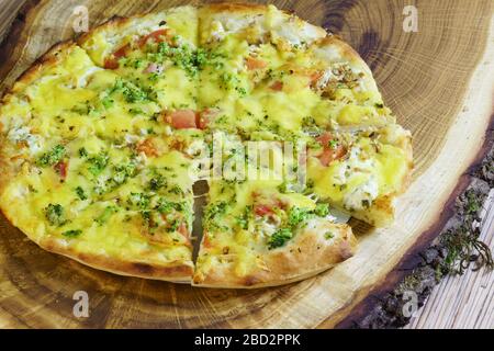 Vegetarische Pizza in Scheiben geschnitten mit Tomaten, Brokkoli und Käse auf einem Holzständer. Selektiver Fokus. Nahaufnahme Stockfoto