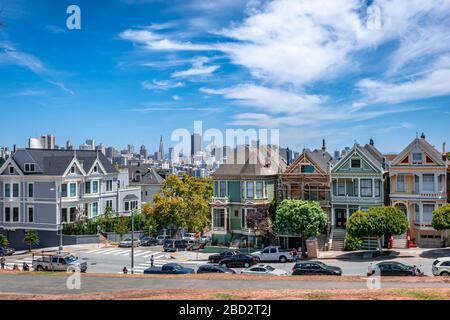 San Francisco, CA/USA - 17. Juli 2015: Die bemalten Damen in der Steiner Street mit Blick auf den Alamo Square und die moderne Skyline der Stadt. Stockfoto