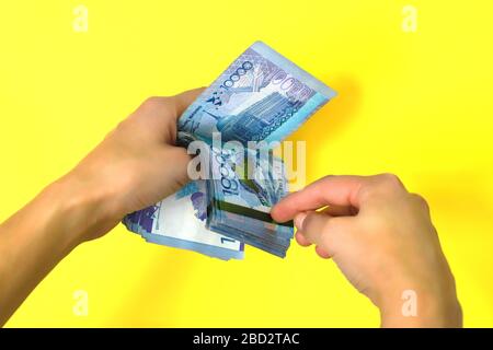 Ein Stapel von Banknoten von zehntausend Tenge. Gelber Hintergrund. Stockfoto
