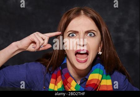 Schockierte junge Frau, die auf ihren Tempel zeigt Stockfoto