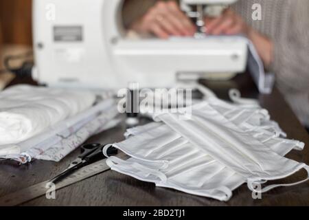 Weibliche Freiwillige nähen zu Hause schützende Antivirenmasken auf einer Nähmaschine Stockfoto