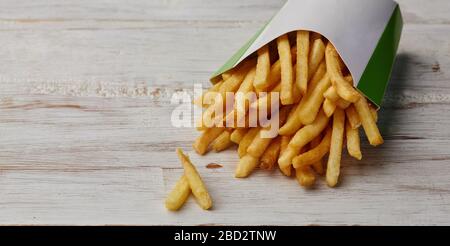 pommes frites in einer Papierverpackung auf Holzhintergrund. Stockfoto