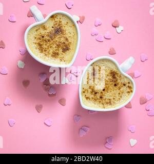 Zwei herzförmige Kaffeetassen auf pastellpinkem Hintergrund, Draufsicht mit Kopierbereich. Konzept der Liebe. Stockfoto