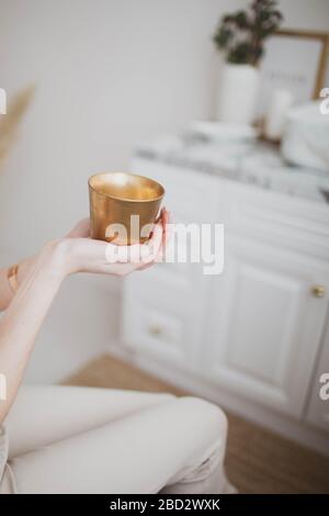 Ein schöner kleiner goldener Kerzenhalter in den Händen einer Frau. Nahaufnahme. Stockfoto