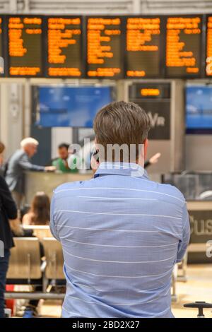 LONDON, ENGLAND - JULI 2018: Mann in den Schalenhülsen auf dem Golfplatz am Bahnhof London Paddington, der die Abfahrt des Zuges beobachtet Stockfoto