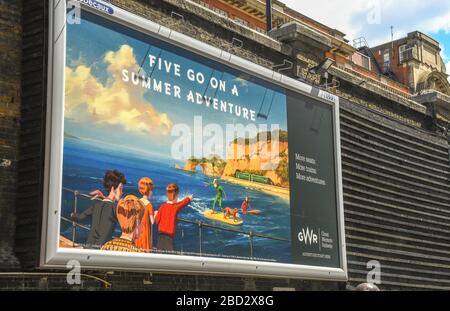 LONDON, ENGLAND - JULI 2018: Großes Werbeplakat an einer Wand außerhalb des Bahnhofs London Paddington. Stockfoto