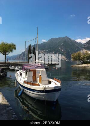 Torbole, Gardasee, Italien - Mai 2017: Im Stillwasser des kleinen Dorfhafens schwimmt ein kleines Boot Stockfoto