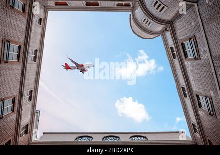 Ein Passagierflugzeug in einem wunderschönen Himmel unter dramatischen Wolken fliegt bei Sonnenuntergang über den Hof. Die gefliesten Häuser in der Stadt Porto in Portugal, unten VI Stockfoto