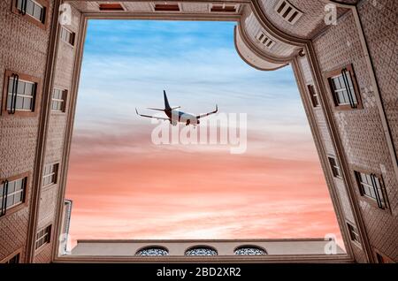 Ein Passagierflugzeug in einem wunderschönen Himmel unter dramatischen Wolken fliegt bei Sonnenuntergang über den Hof. Die gefliesten Häuser in der Stadt Porto in Portugal, unten VI Stockfoto