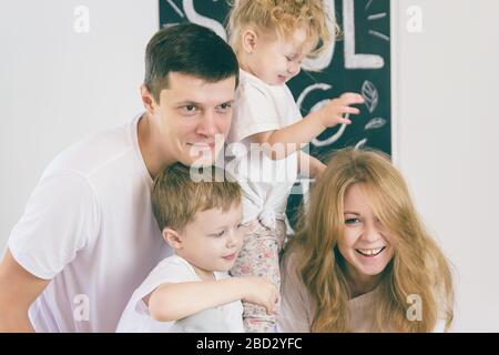 Glückliche Eltern mit ihren Kindern freuen sich im Leben. Das Mädchen spielt mit Mama 's Haar. Stockfoto