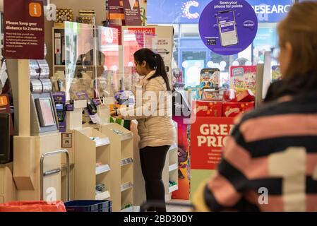 Shopper vor einem Perspex-Bildschirm zum Schutz der Mitarbeiter, installiert in einem Sainsbury's lokalen Supermarkt in Oxford während der Covid-19-Pandemie von 2020 Stockfoto