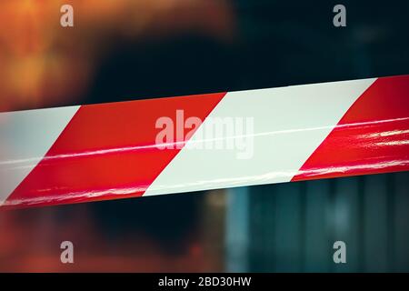 Rot-weißes, gestreiftes Schutzband schützt den umschlossenen Bereich, Reparaturarbeiten. Industrieller, kunstvoller Hintergrund. Stockfoto