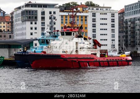 Schleppboot BB Arbeiter im Hafen von Bergen, Norwegen. Ein regnerischer und nebeliger Tag. TUG Boot Vivax im Hintergrund Stockfoto