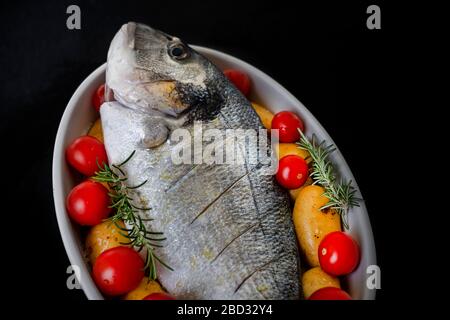 Brassen auf Platte mit Kartoffeln und Tomaten Stockfoto
