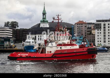 Schleppboot BB Coaster, Abfahrt vom Hafen von Bergen, Norwegen. Nykirken Kirche im Hintergrund Stockfoto