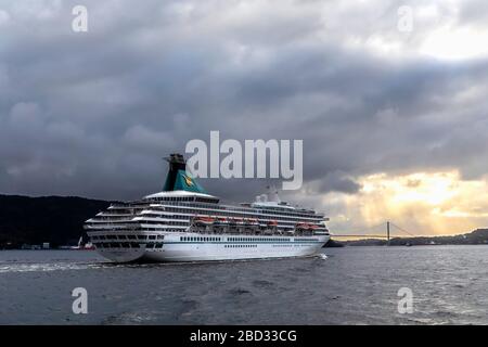 Kreuzfahrtschiff Artania (Baujahr 1984) in Byfjorden, Abfahrt vom Hafen von Bergen, Norwegen. Ein grauer und regnerischer Tag. Sich nähernde Askoeybroen-Hängebrücke Stockfoto