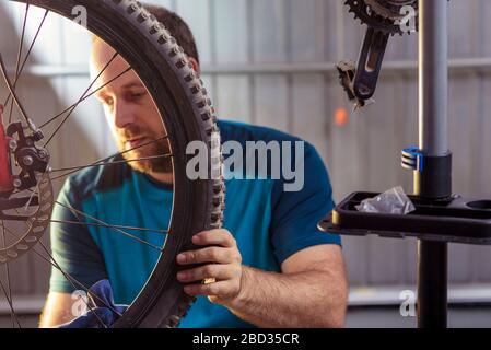 Mechaniker in einer Fahrradreparaturwerkstatt Ölen der Kette von einem Fahrrad. Mann sein Fahrrad für die neue Saison beibehalten. Arbeitsprozess. Stockfoto