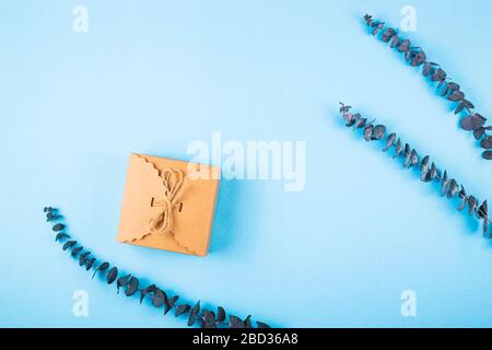 Geschenkschachtel und Eukalyptus auf blauem Hintergrund mit Copyspace. Stockfoto