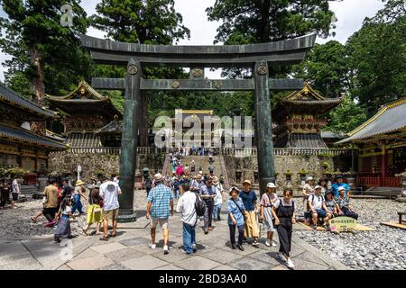 Nikko, Japan, August 2019 - Menge von Touristen, die unter einem Torii-Tor am Eingang des Toshogu-Schreins, eines der beliebtesten Reiseziele, vorbeikommen Stockfoto