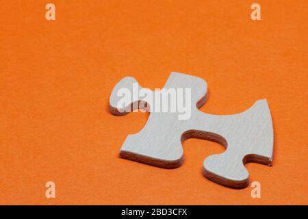 Ein Puzzleteil aus Holz auf orangefarbenem Hintergrund Stockfoto