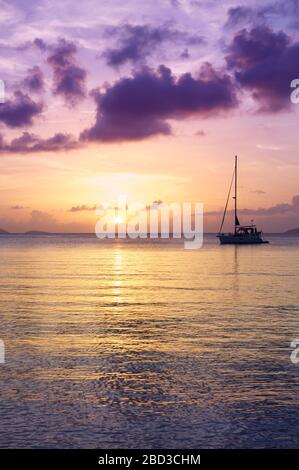 Malerischer Sonnenuntergang mit tropischen lila Wolken, die sich auf dem ruhigen karibischen Meer spiegeln Stockfoto