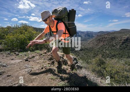 Mann balanciert, während er den Weg hinauf wandert, Blick auf die Berge im Hintergrund Stockfoto