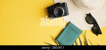Flaches, weibliches Modeoutfit im Sommer auf gelbem Hintergrund mit Strohhut, Sonnenbrille, Palmblatt, Kamera und Pass. Draufsicht Urlaub concep Stockfoto