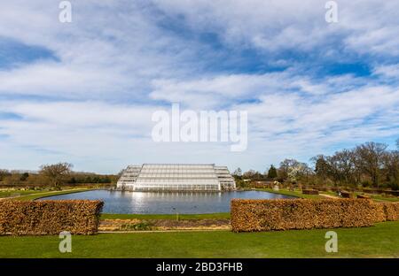 Die moderne Architektur Glasshouse im RHS Garden, Wisley, Surrey im Frühling mit trübem blauem Himmel Stockfoto