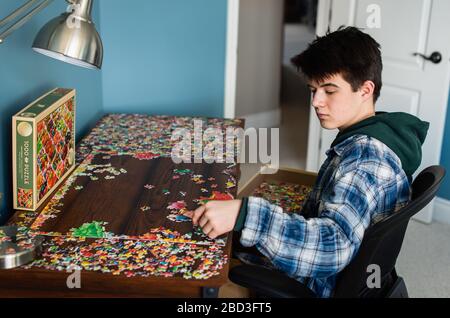 Teen Junge arbeitet an einem Puzzle in seinem Schlafzimmer während Covid 19. Stockfoto