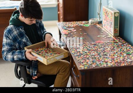 Teen Junge arbeitet an einem Puzzle in seinem Schlafzimmer während Covid 19. Stockfoto