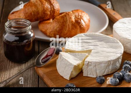 Camembert Käse, Marmelade, Blaubeeren und Croissants auf Holztisch Stockfoto