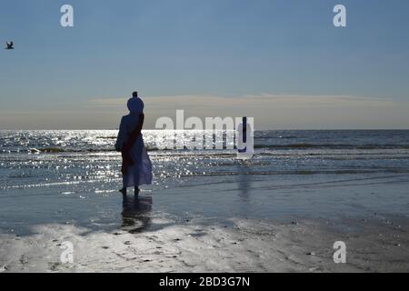 Schwarze Frauen in weißen Gewändern beten am Strand von Galveston, Texas Stockfoto