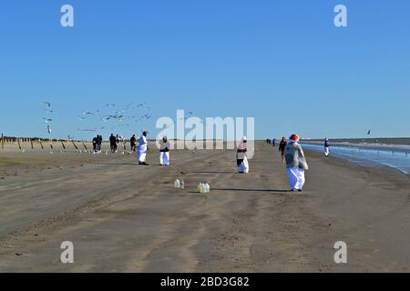 Schwarze Frauen in weißen Gewändern beten am Strand von Galveston, Texas Stockfoto