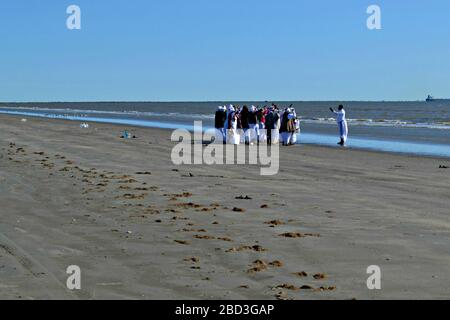 Schwarze Frauen und ein Priester beten am Strand von Galveston, Texas Stockfoto