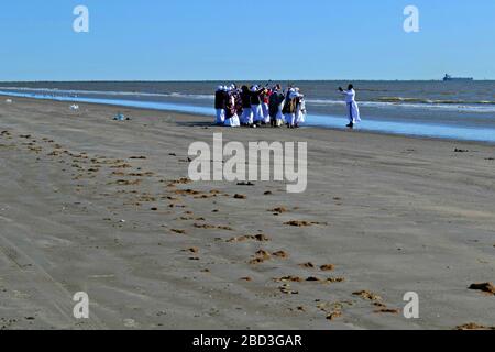 Schwarze Frauen und ein Priester beten am Strand von Galveston, Texas Stockfoto