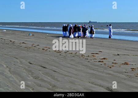 Schwarze Frauen und ein Priester beten am Strand von Galveston, Texas Stockfoto